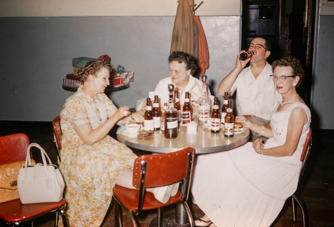 History of slang - A group of people sitting around a table with bottles of beer